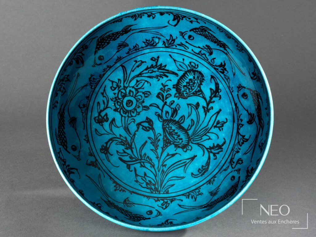 Plat circulaire en faïence bleu turquoise décoré de fleurs et de poissons