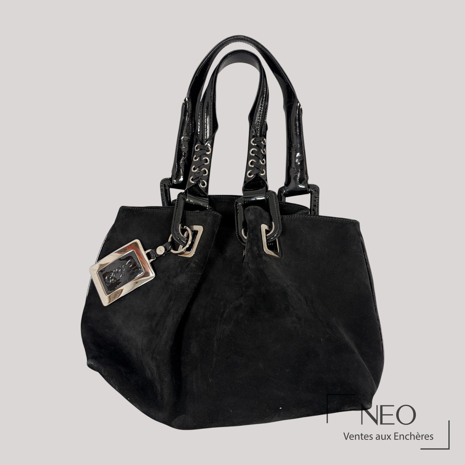 Sac noir en daim avec anses brillantes et bijou de sac rectangulaire.